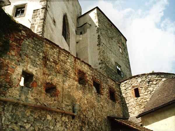 parkánová hradba jádra s obloukem bašty, v pozadí věž s kaplí a východní věž jádra